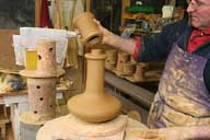 Reportage sur la fabrication d'un épi de faîtage dans l'atelier de poterie. Tournage : emboîtement de la coupe et du manchon de l'élément central.