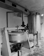 Atelier de fabrication, dit de pesage de la nitroglycérine. Vue intérieure. Détail : cuve de stockage de la nitroglycérine (à droite) et balance (à gauche).