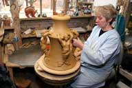 Reportage sur la fabrication d'un épi de faîtage dans l'atelier de poterie. Décoration de la base de l'épi : apposition des pièces moulées sur la base.