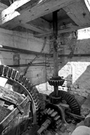 Atelier de fabrication. Vue intérieure. Mécanisme d'entraînement des meules du moulin, rouet et engrenages.