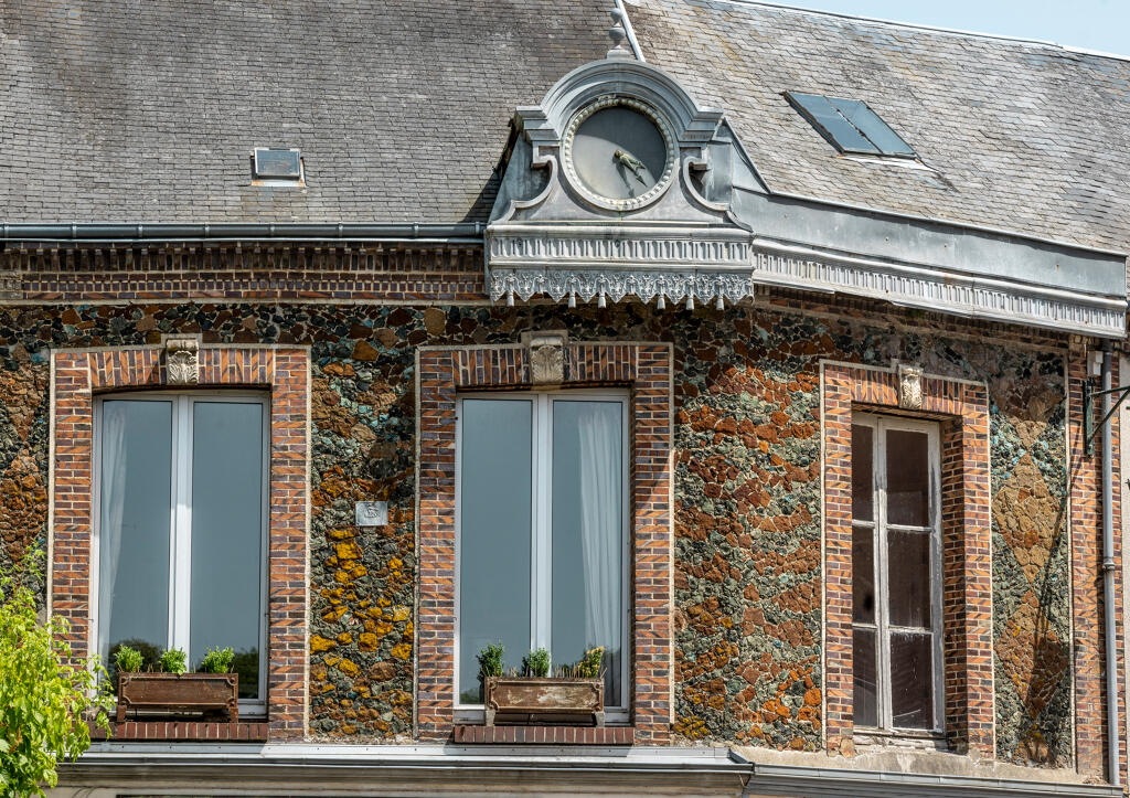 N°20 place de l'Hôtel de Ville : vue de détail de l'étage de la maison à boutique aux murs ornés d'un parement en mosaïque d'éclats de laitier.