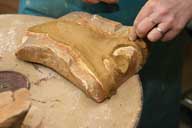 Reportage sur la fabrication d'un épi de faîtage dans l'atelier de poterie. Estampage : remplissage de la partie arrière du moule sirène (2).