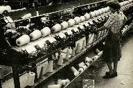 Ouvrière contrôlant le fonctionnement d'une machine à bobiner.- Photographie ancienne, photogr. Studio Desaunay, Condé-sur-Noireau, [circa 1947-1948]. (Collection particulière Verrier).