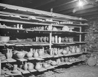 Intérieur du séchoir : planches de poteries disposées sur des étagères de séchage.