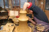 Reportage sur la fabrication d'un épi de faîtage dans l'atelier de poterie. Tournage : assemblage des parties basse et haute de la base de l'épi.