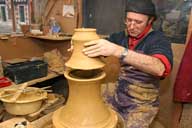 Reportage sur la fabrication d'un épi de faîtage dans l'atelier de poterie. Tournage : assemblage des parties basse et haute de la base de l'épi, superposition.