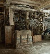 Atelier de fabrication, vue intérieure du rez-de-chaussée : rouet et engrenages avec beffroi, piliers bois et armature métallique.