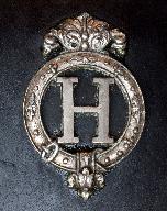 Le H des haras nationaux en métal argenté sur un harnais.