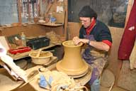 Reportage sur la fabrication d'un épi de faîtage dans l'atelier de poterie. Tournage : façonnage de la partie basse de la base de l'épi.