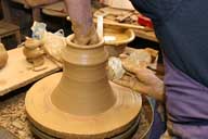Reportage sur la fabrication d'un épi de faîtage dans l'atelier de poterie. Tournage : lissage à l'aide d'un racleur.