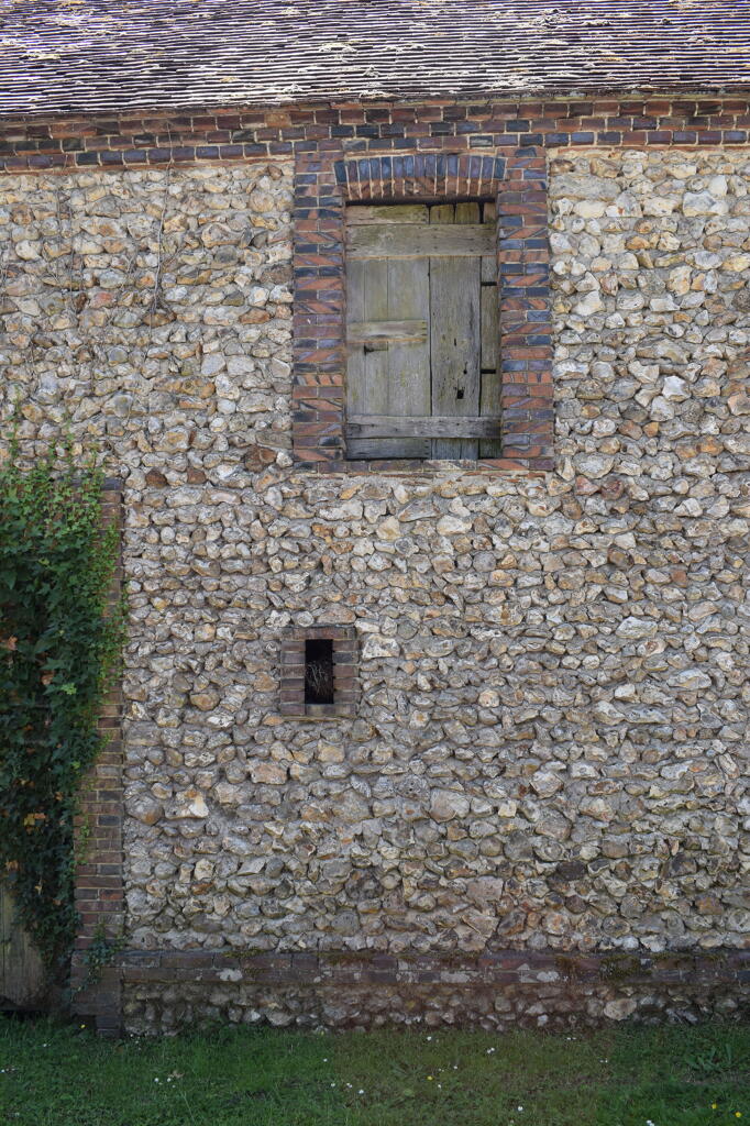 Dépendance à l’extrémité ouest du village : mise en œuvre en moellons de silex, encadrements de baies en brique.