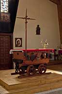 Autel de la chapelle reposant sur un wagonnet de mine, orné de l'équipement du mineur (casque, marteau, lanterne) et d'une croix formée par des pioches.